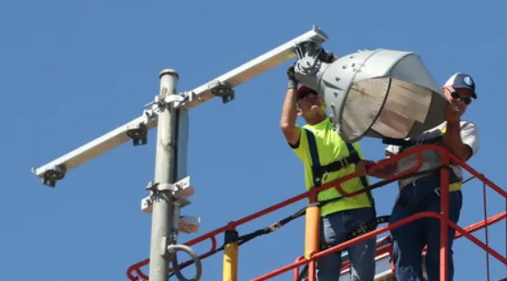 Crew removing a traditional metal-halide floodlight